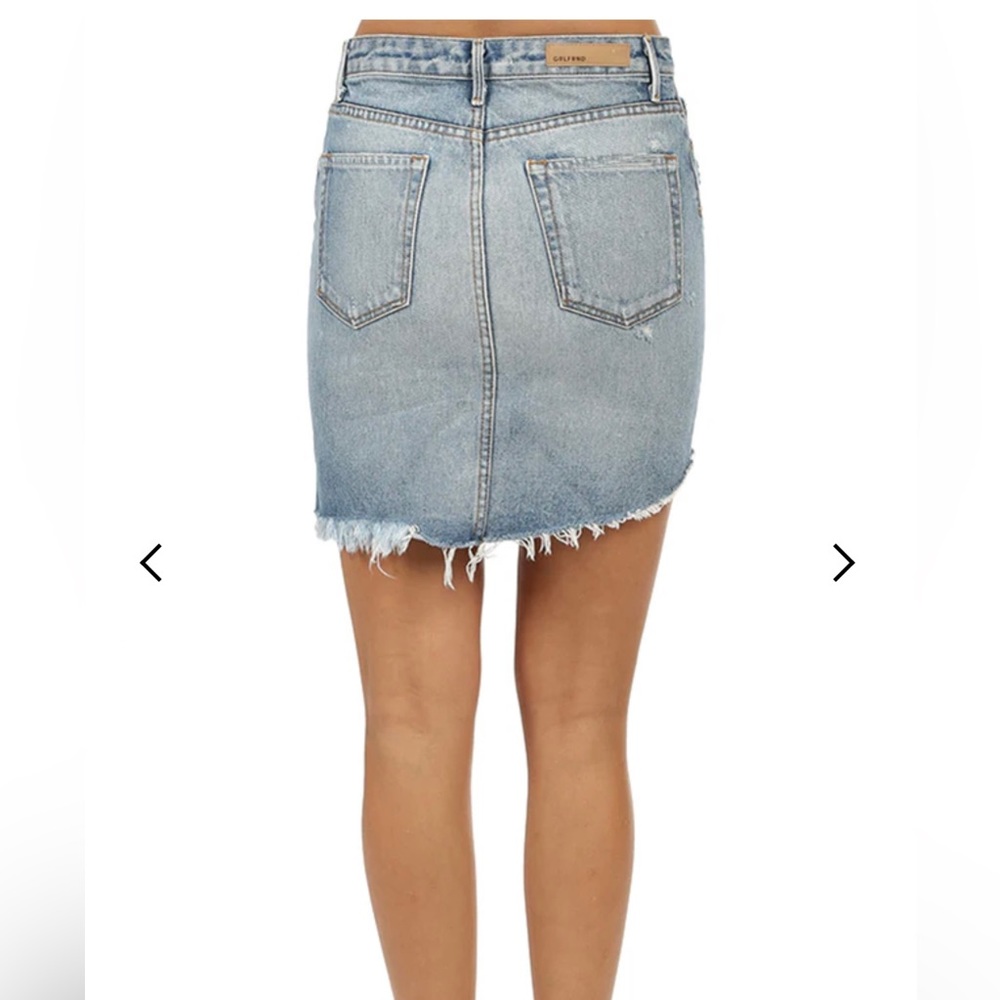 An asymmetric scooped hem. A mid rise waist is closed with a button fly.